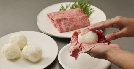 Take a handful cooked rice, roll it between the hands to make a rice ball. Wrap each rice ball with a slice of Kagoshima Wagyu beef.